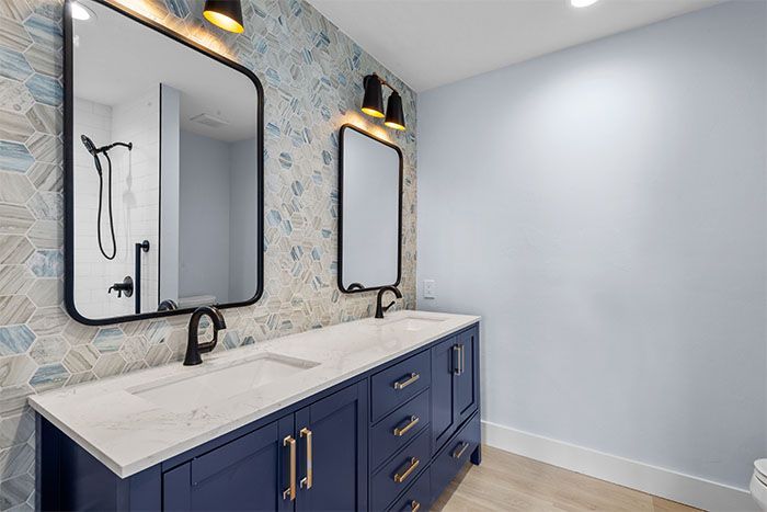 A bathroom with two sinks , two mirrors and a toilet.