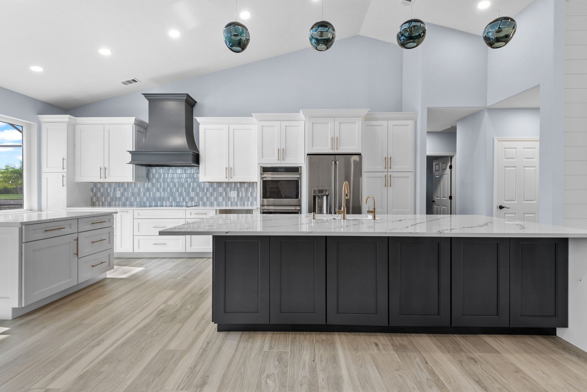 A kitchen with white cabinets and a large island in the middle.