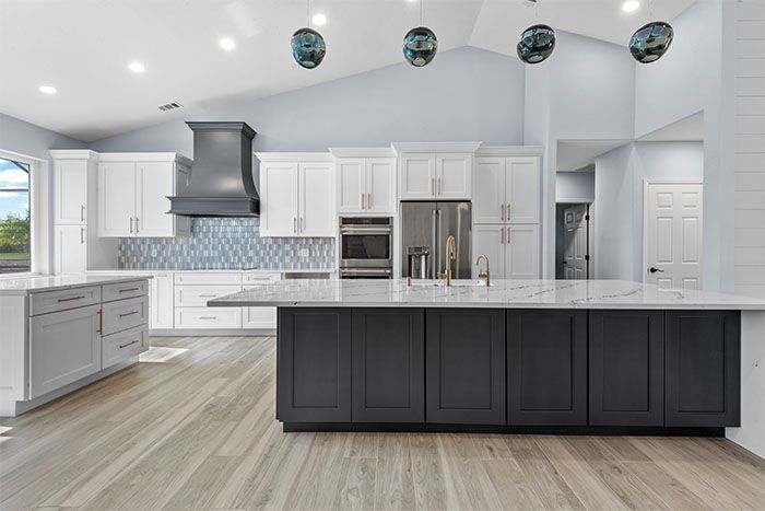 A kitchen with white cabinets and a large island in the middle.