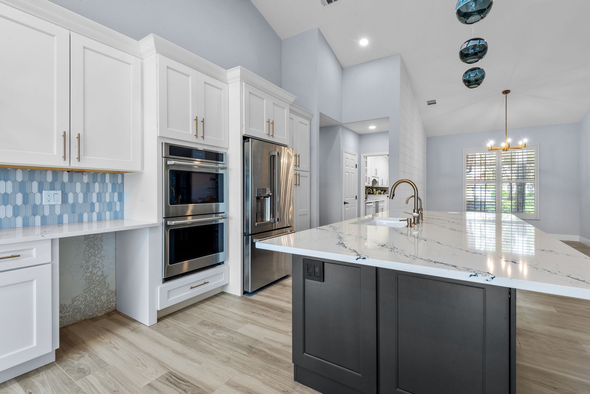 A kitchen with white cabinets , stainless steel appliances , and a large island.
