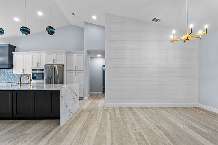 A kitchen with a large island in the middle of the room and a chandelier hanging from the ceiling.