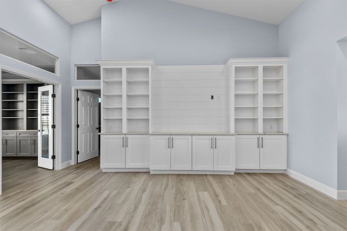An empty living room with hardwood floors and white cabinets.