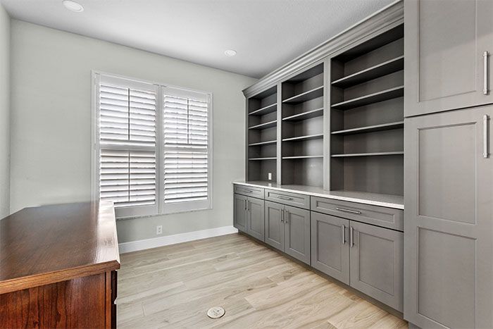 A room with lots of shelves and cabinets and a window.