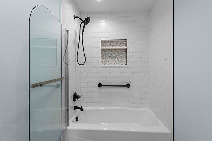 A bathroom with a bathtub and a shower with a glass door.