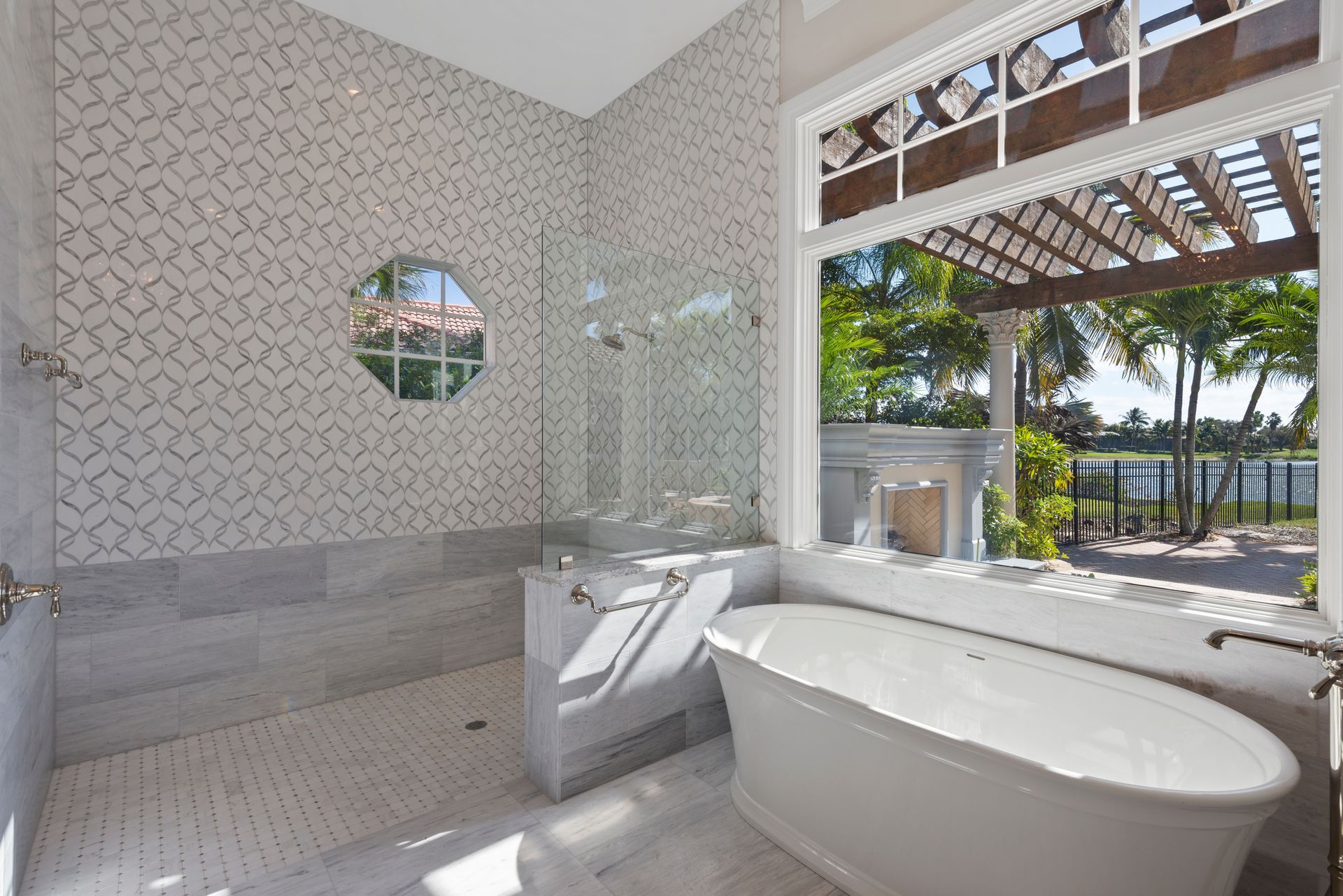 A bathroom with a tub , shower , mirror and window.