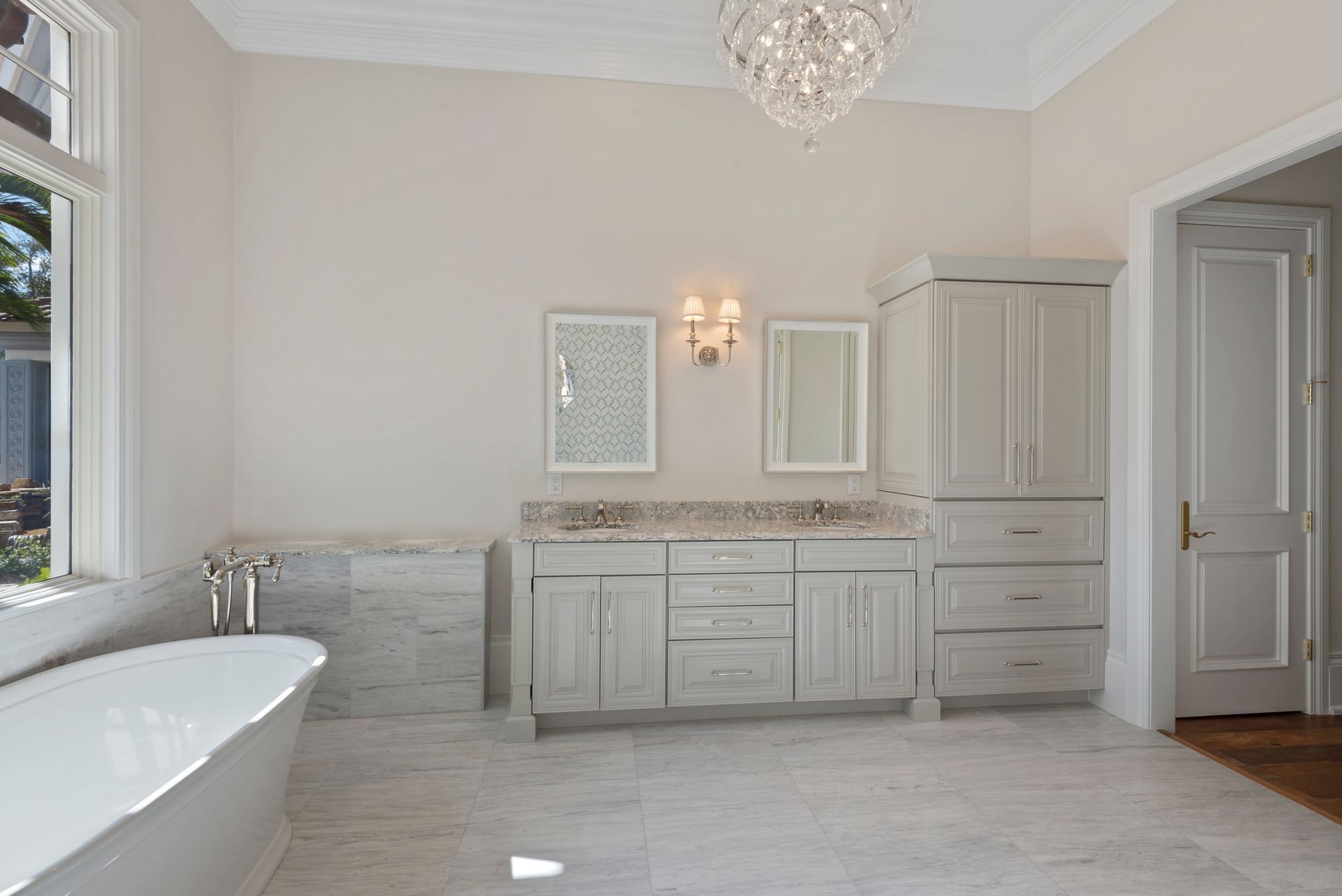 A bathroom with a bathtub , sinks , cabinets and a chandelier.
