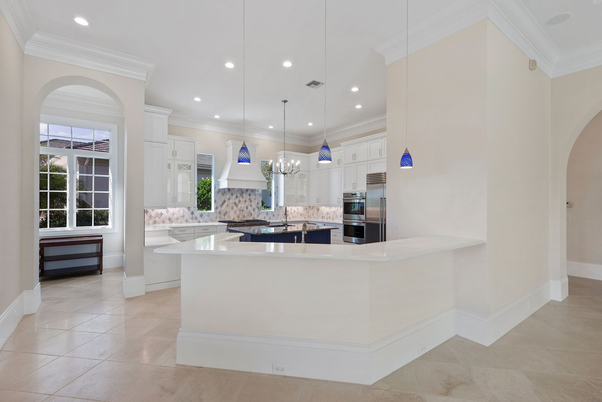 A kitchen with white cabinets , stainless steel appliances , and a large island.