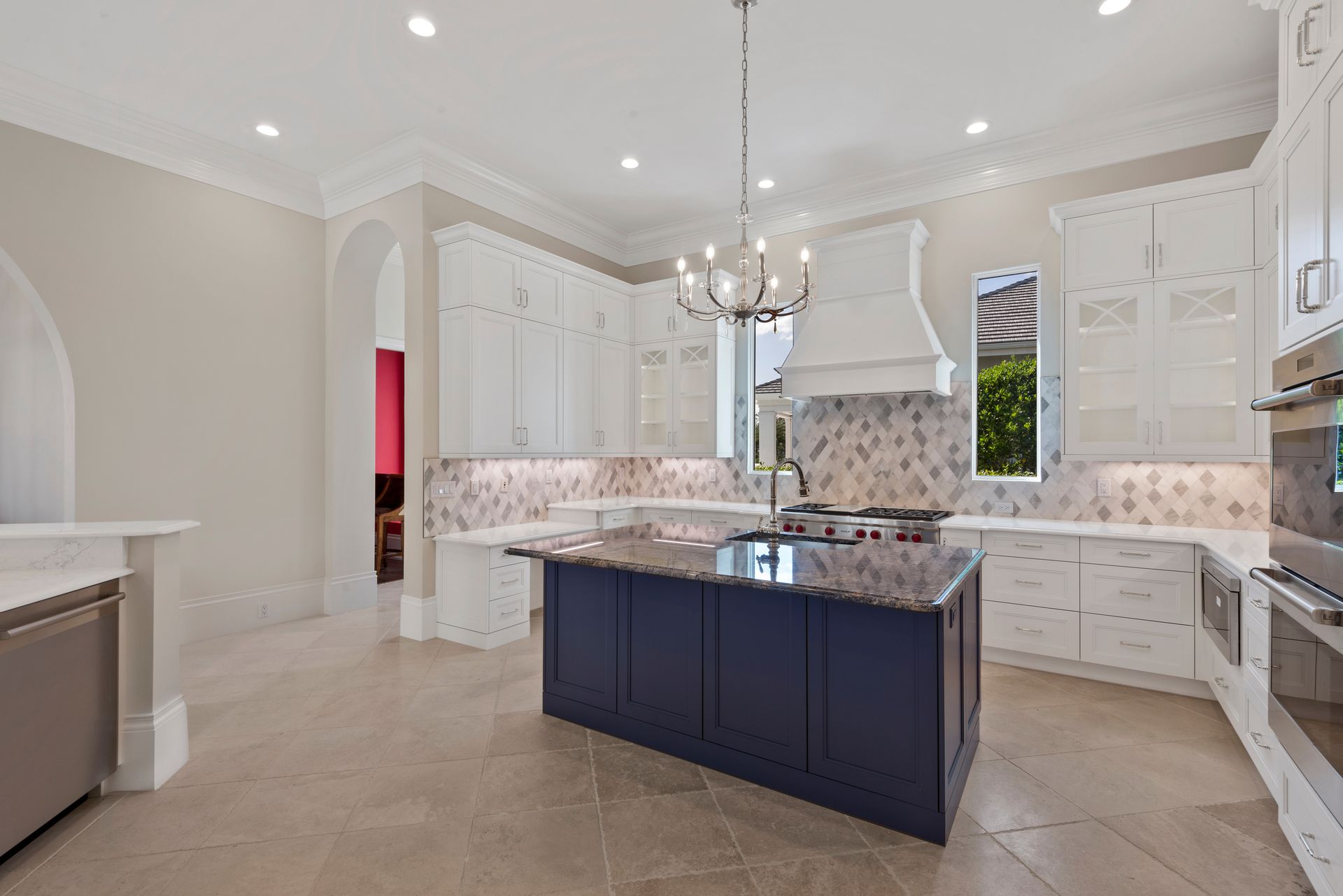 A large kitchen with a large island in the middle and a chandelier hanging from the ceiling.