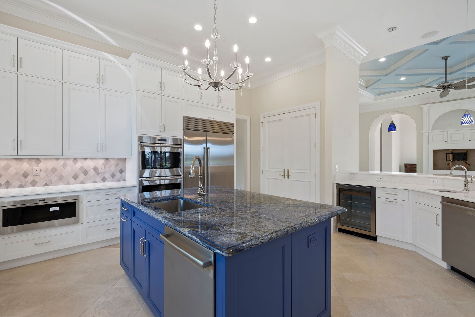 A kitchen with white cabinets and a blue island