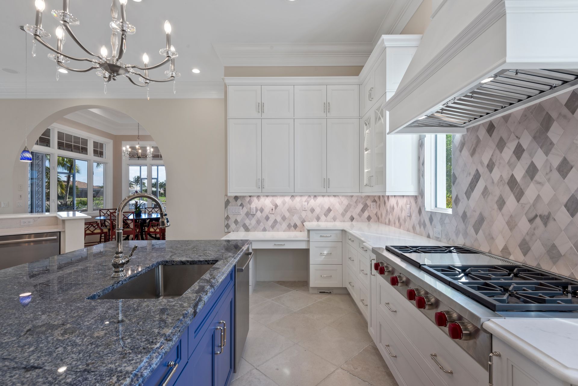 A kitchen with a stove , sink , and chandelier.