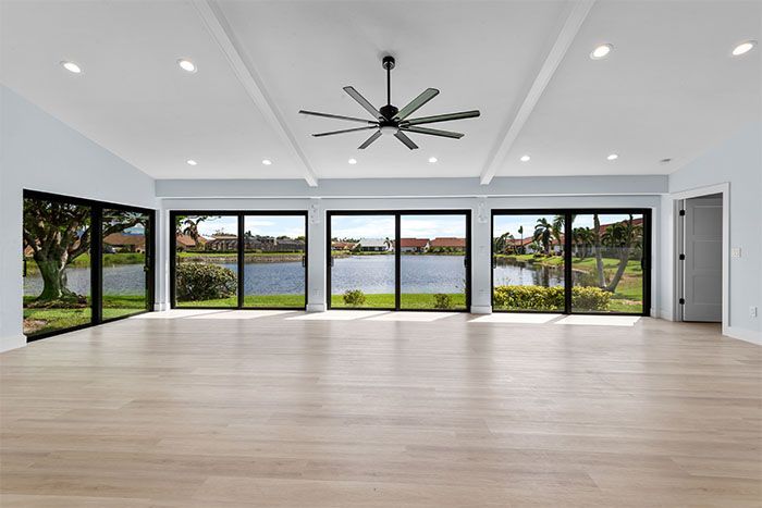A large empty room with a lot of windows and a ceiling fan.