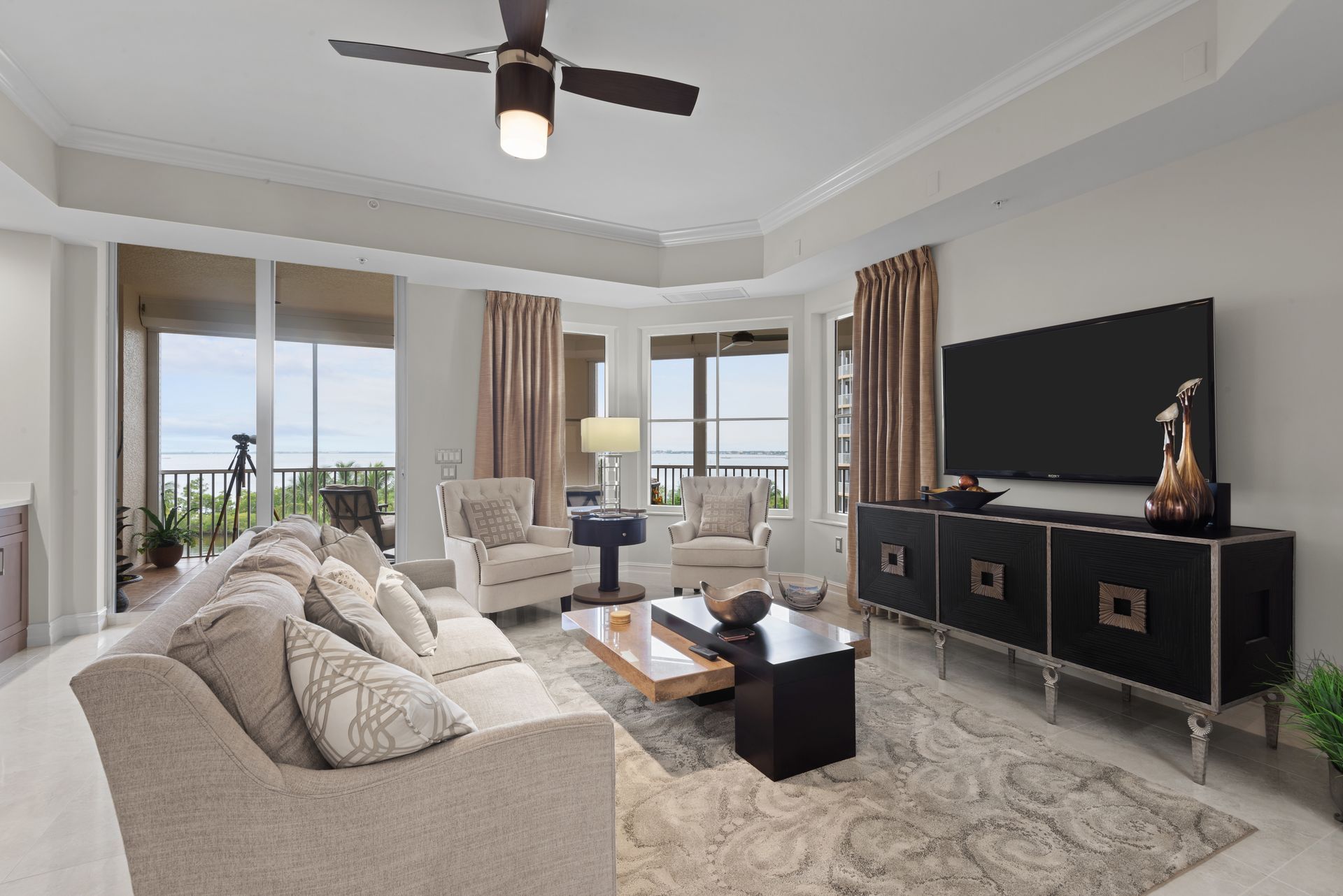 A living room with a ceiling fan and a flat screen tv