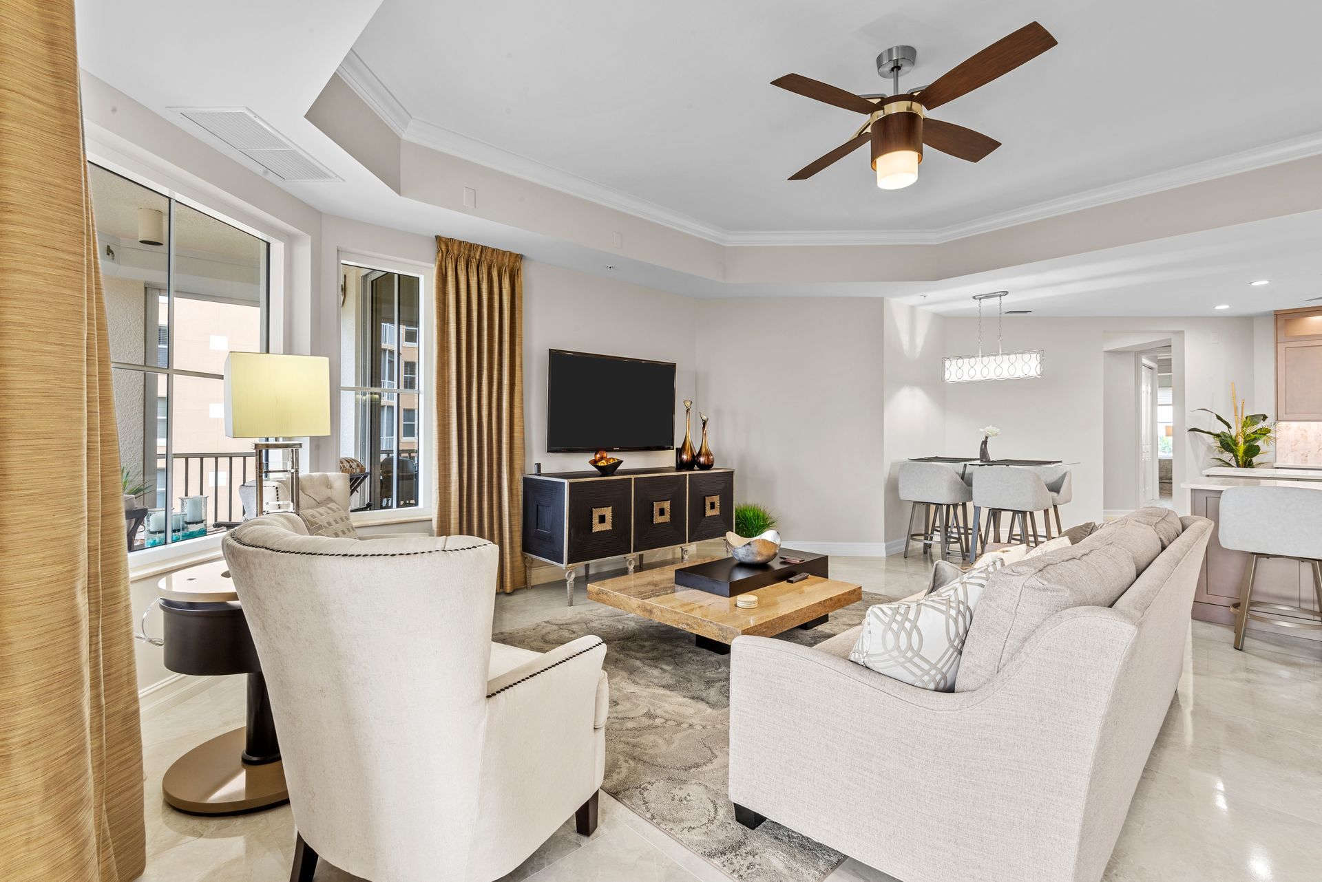 A living room with a couch , chairs , coffee table , television and ceiling fan.