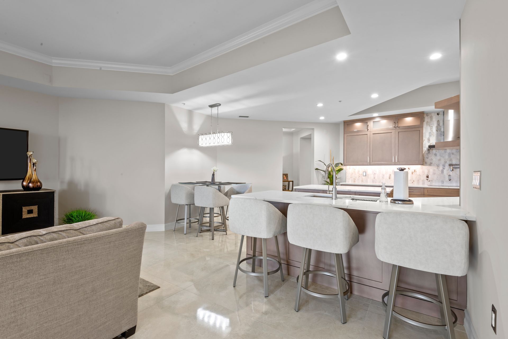 A living room with a couch , bar stools and a television.