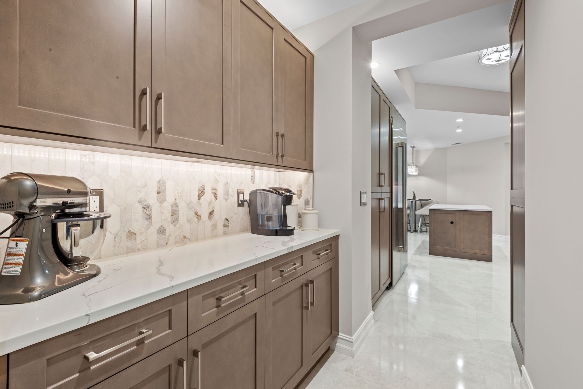 A kitchen with brown cabinets and white counter tops and a mixer on the counter.