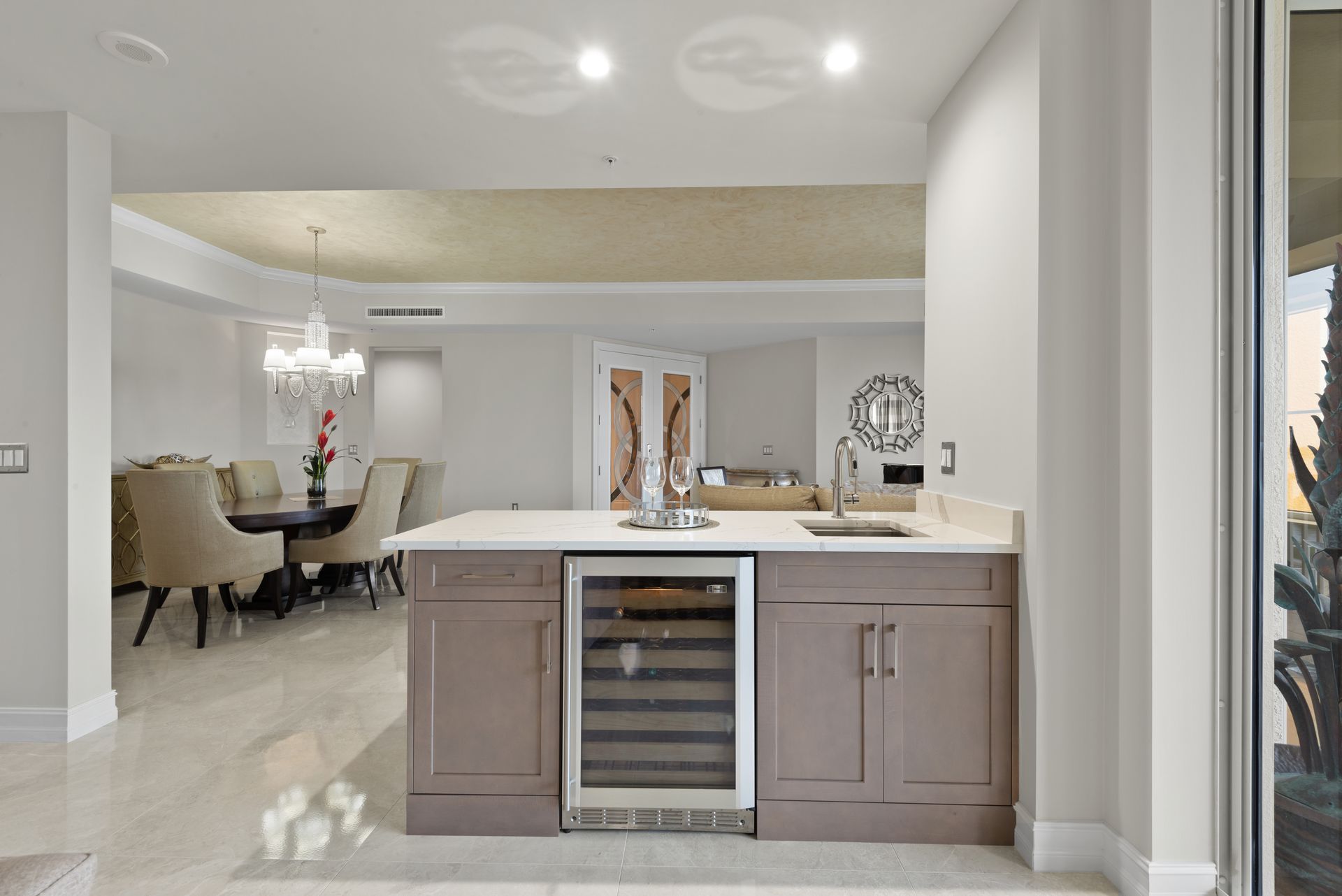 A kitchen with a refrigerator and a sink and a dining room in the background.