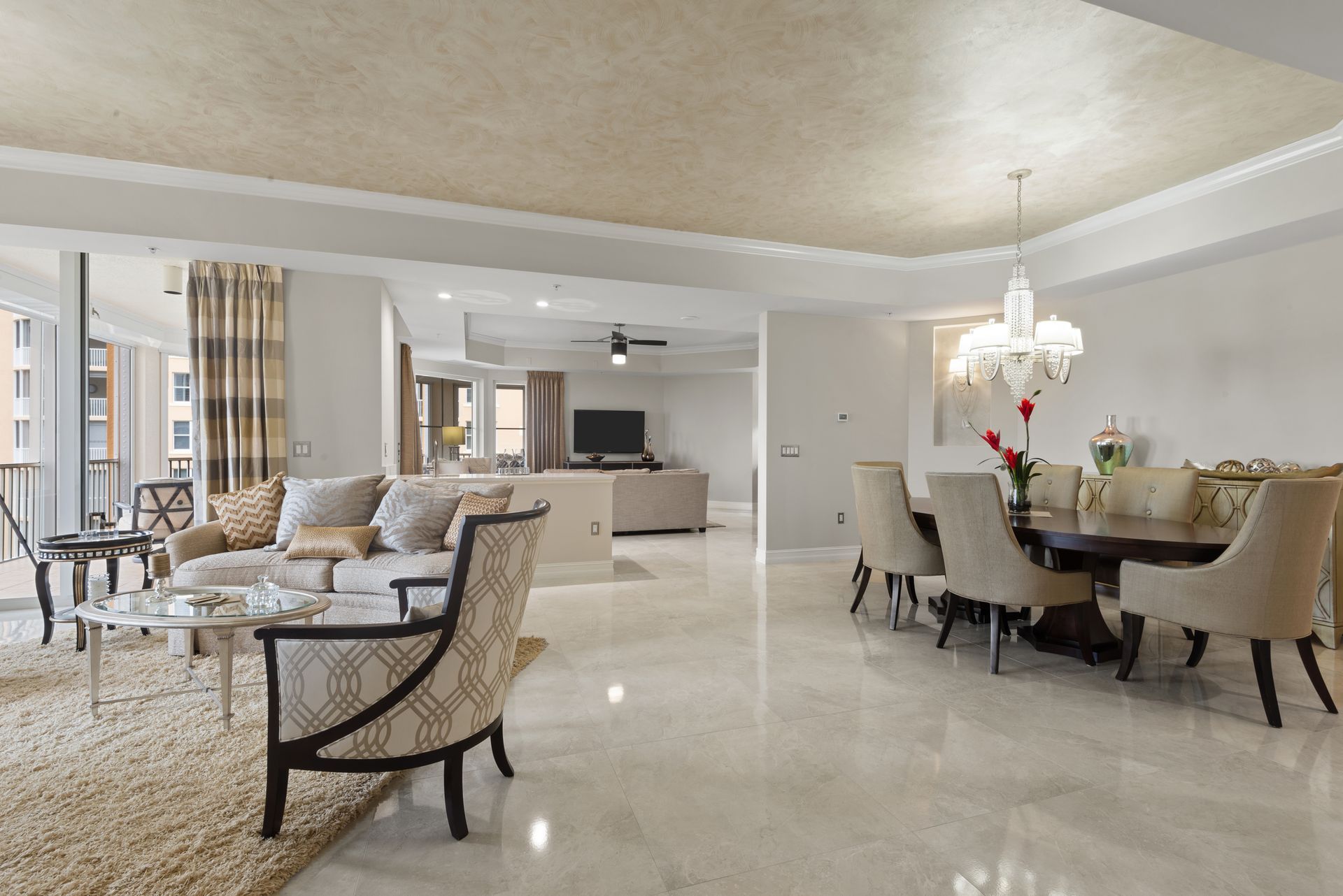 A living room with a couch , chairs , a table and a chandelier.