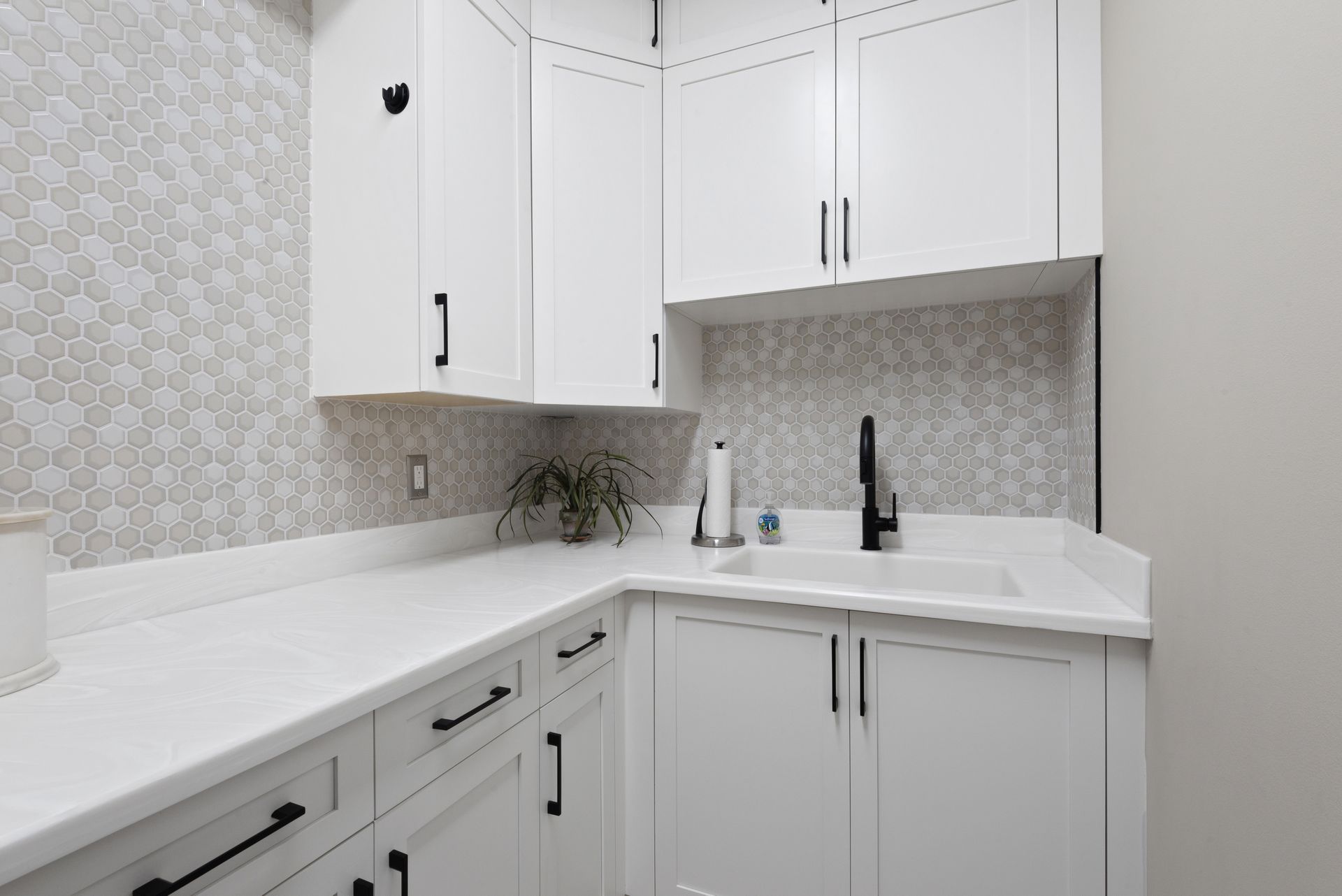 A kitchen with white cabinets and black handles and a sink.