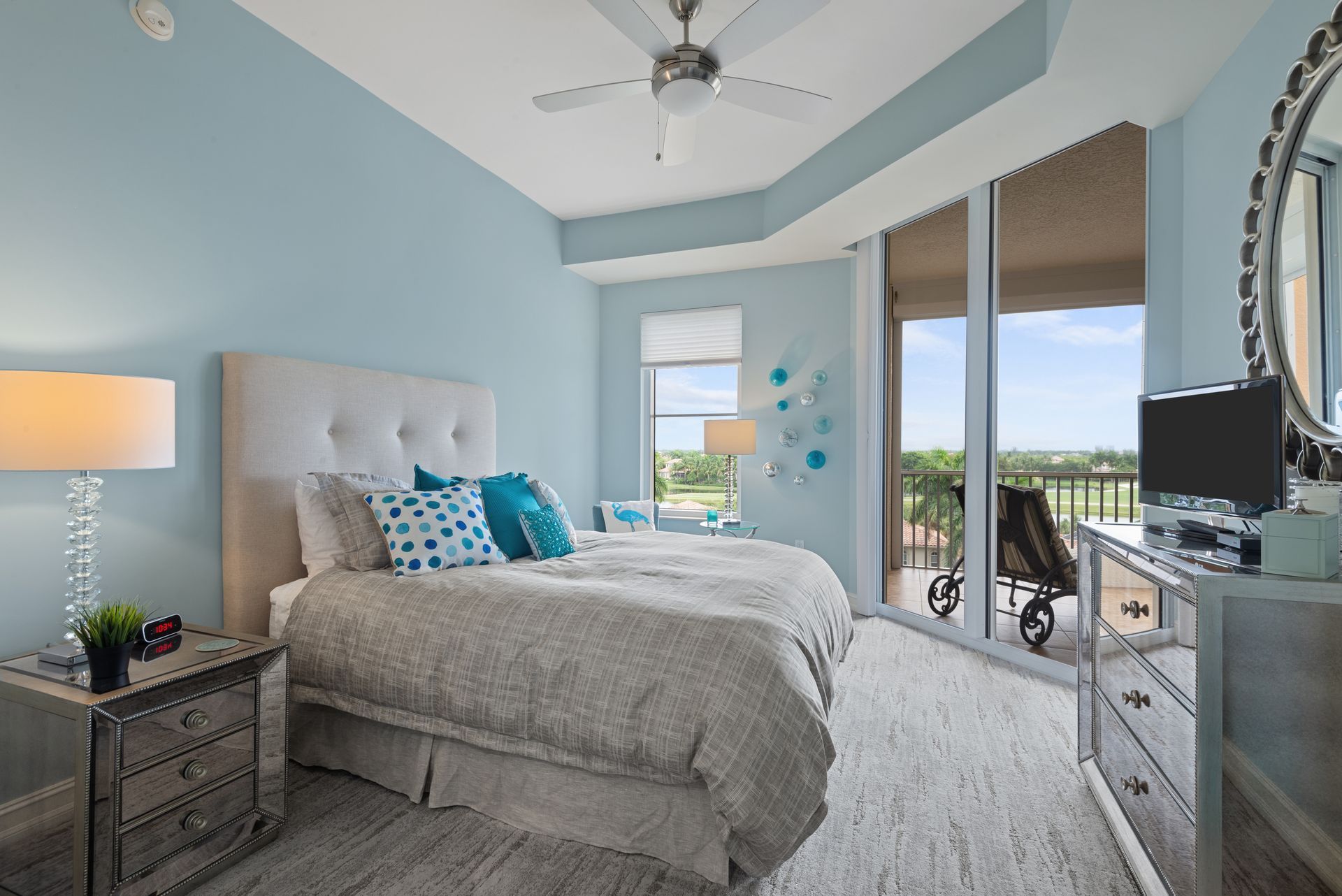 A bedroom with two beds , a dresser , a mirror and a ceiling fan.