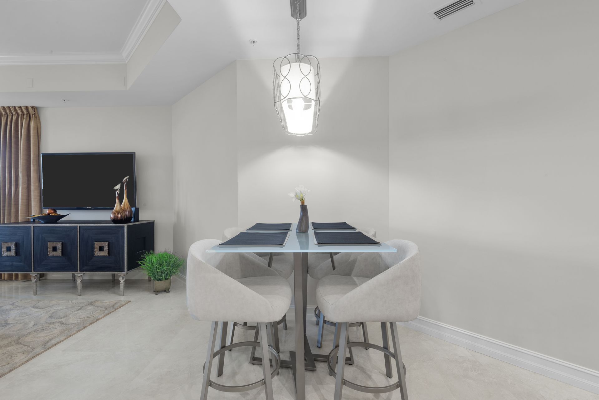 A dining room with a table and chairs and a television.