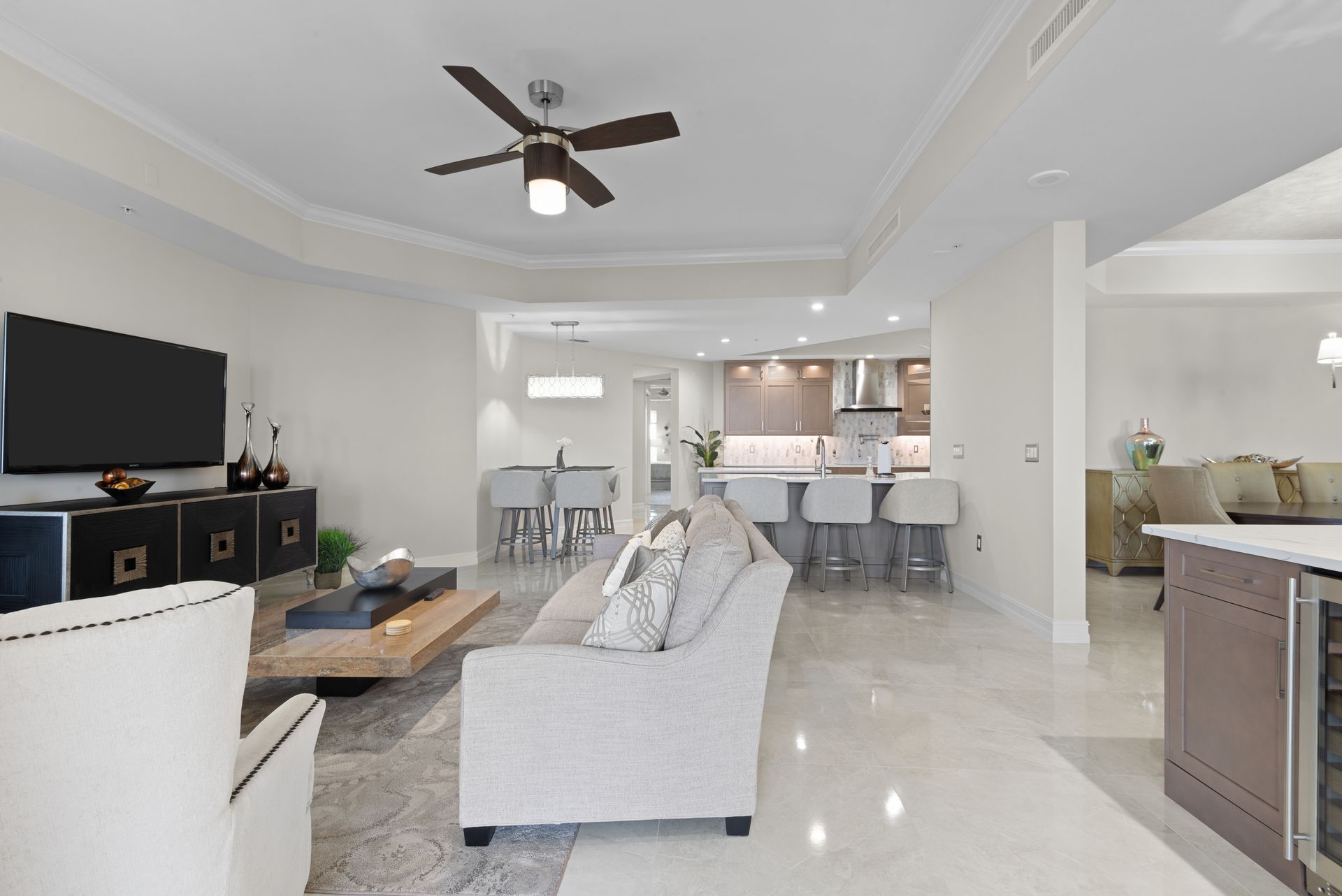 A living room with a ceiling fan and a flat screen tv