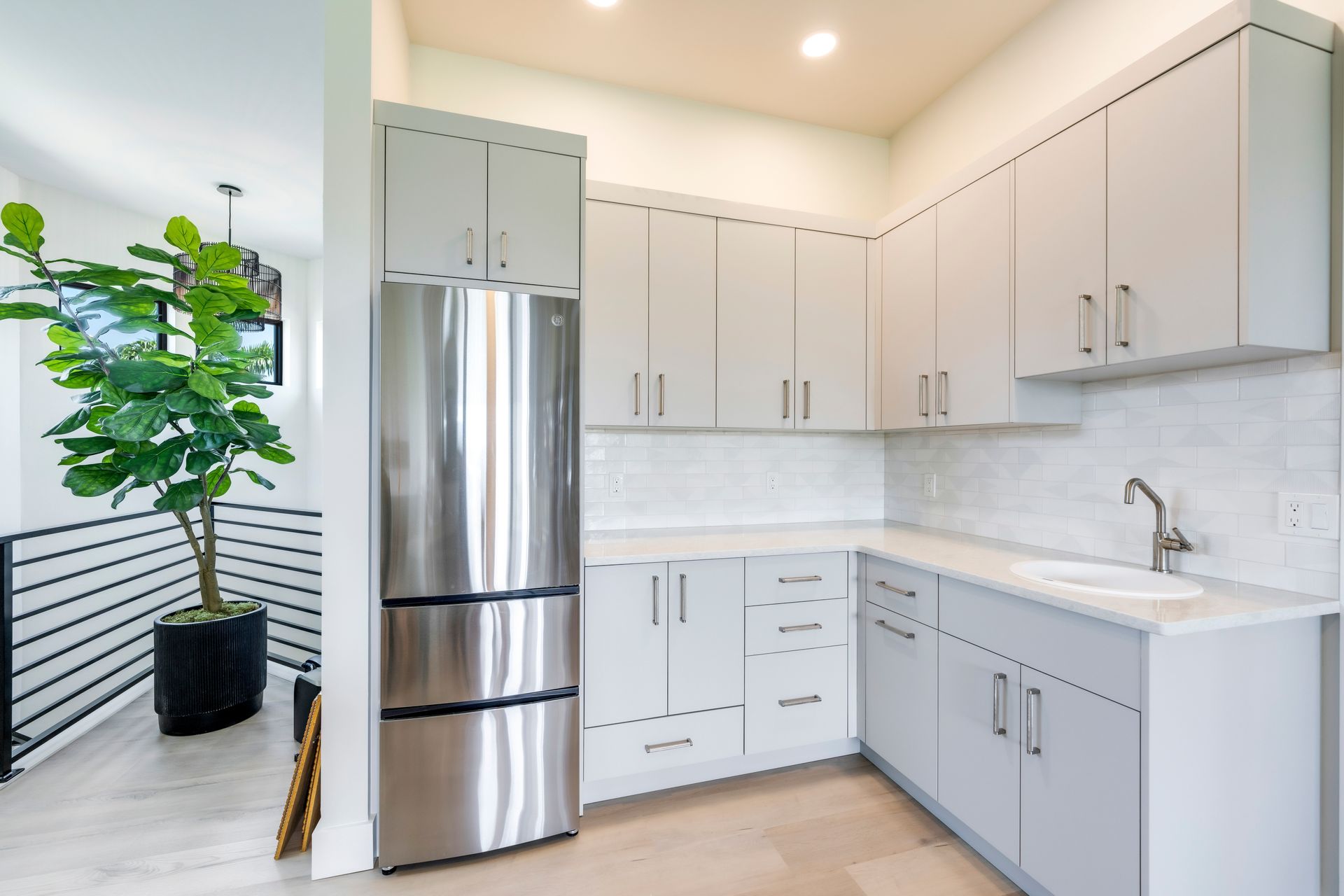 A kitchen with white cabinets and a stainless steel refrigerator