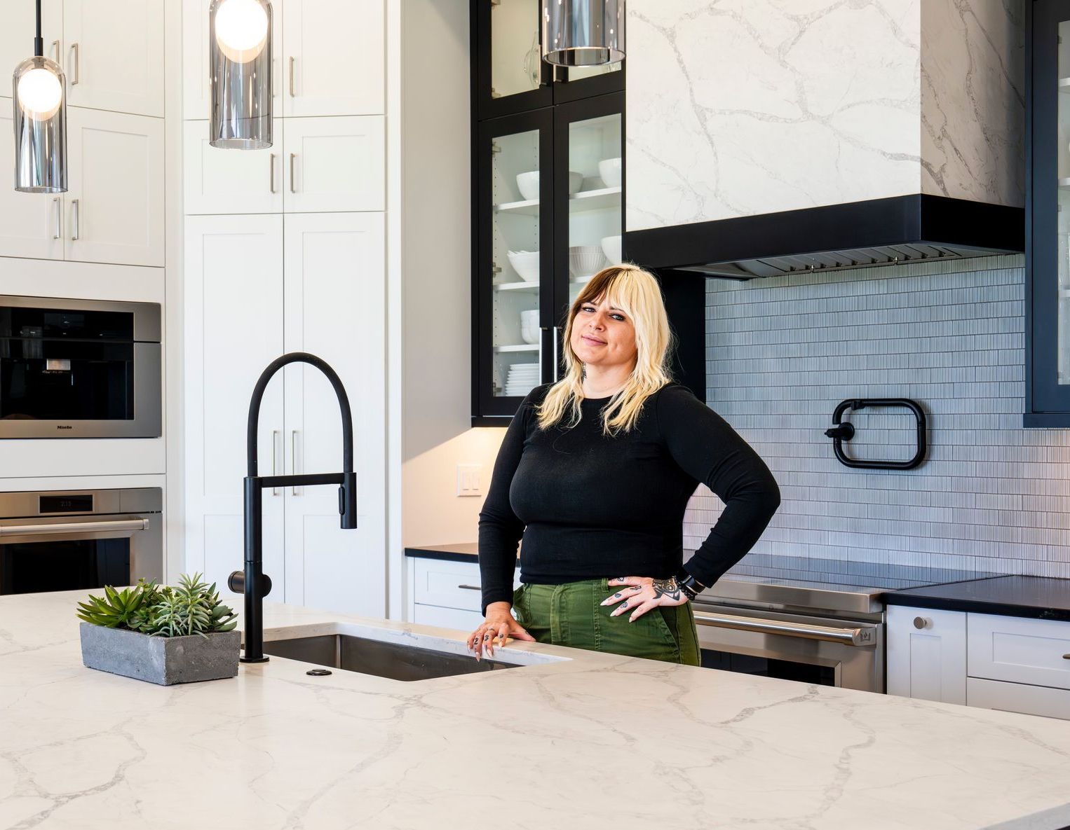 A woman is standing in a kitchen next to a sink.