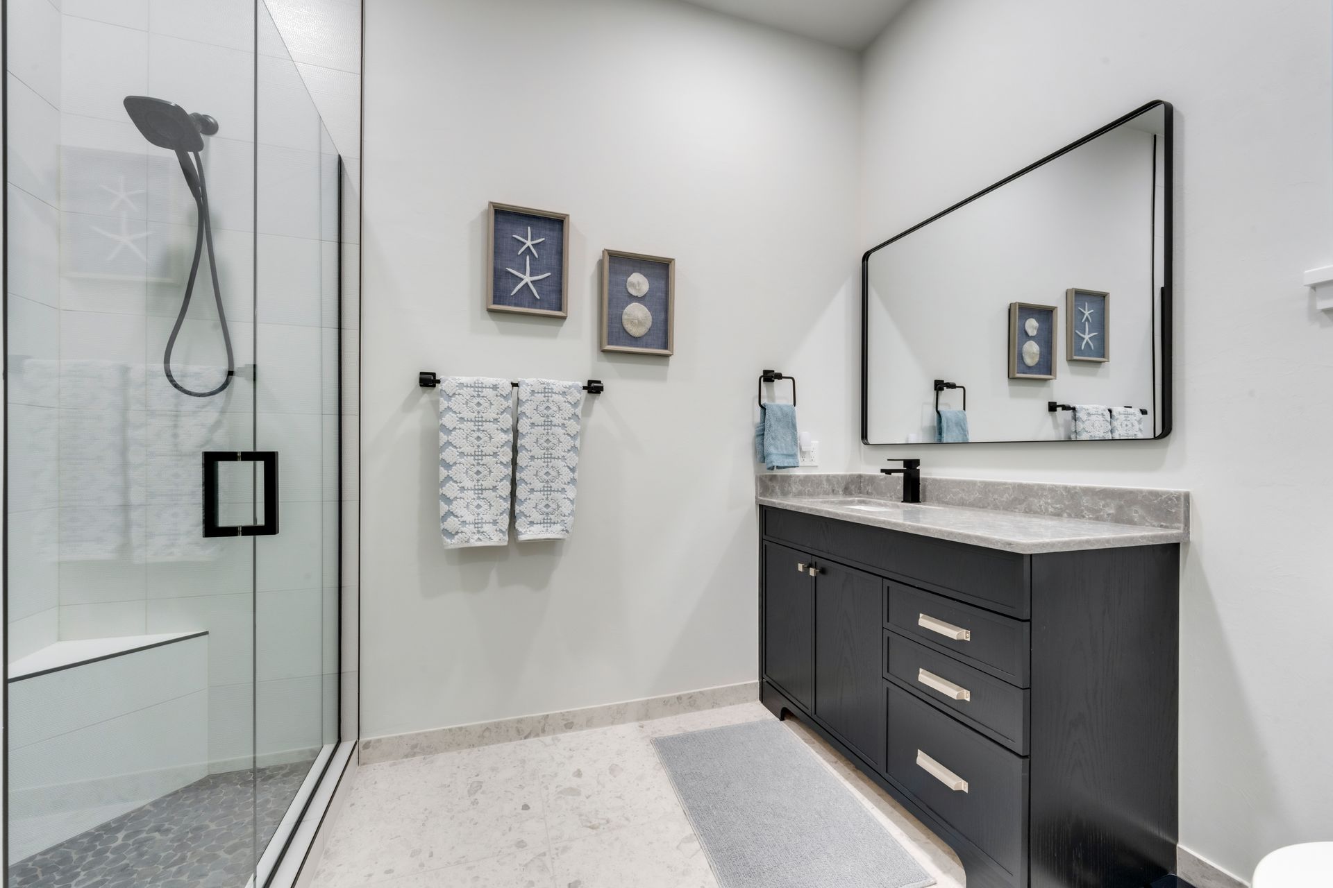 A bathroom with a walk in shower , sink , mirror and toilet.
