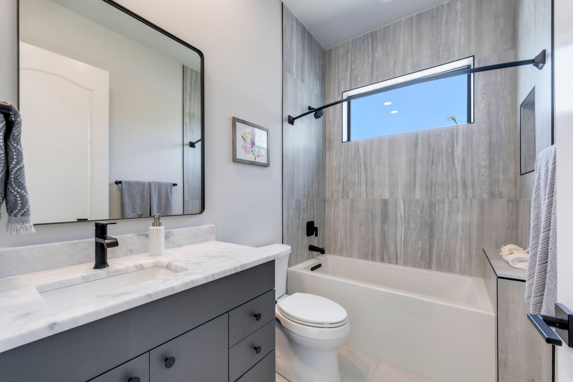 A bathroom with a toilet , sink , tub and mirror.