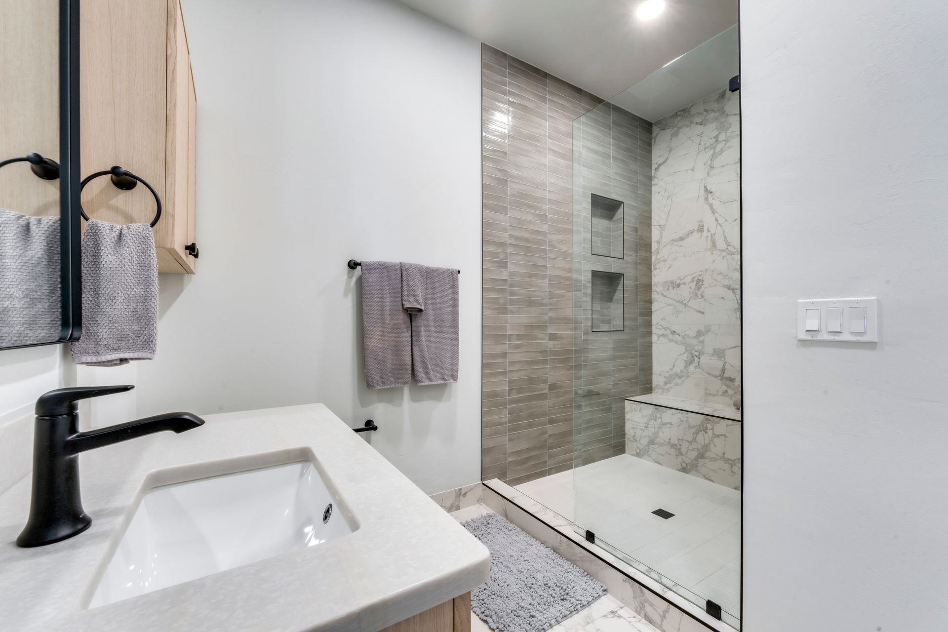 A bathroom with a sink and a walk in shower.
