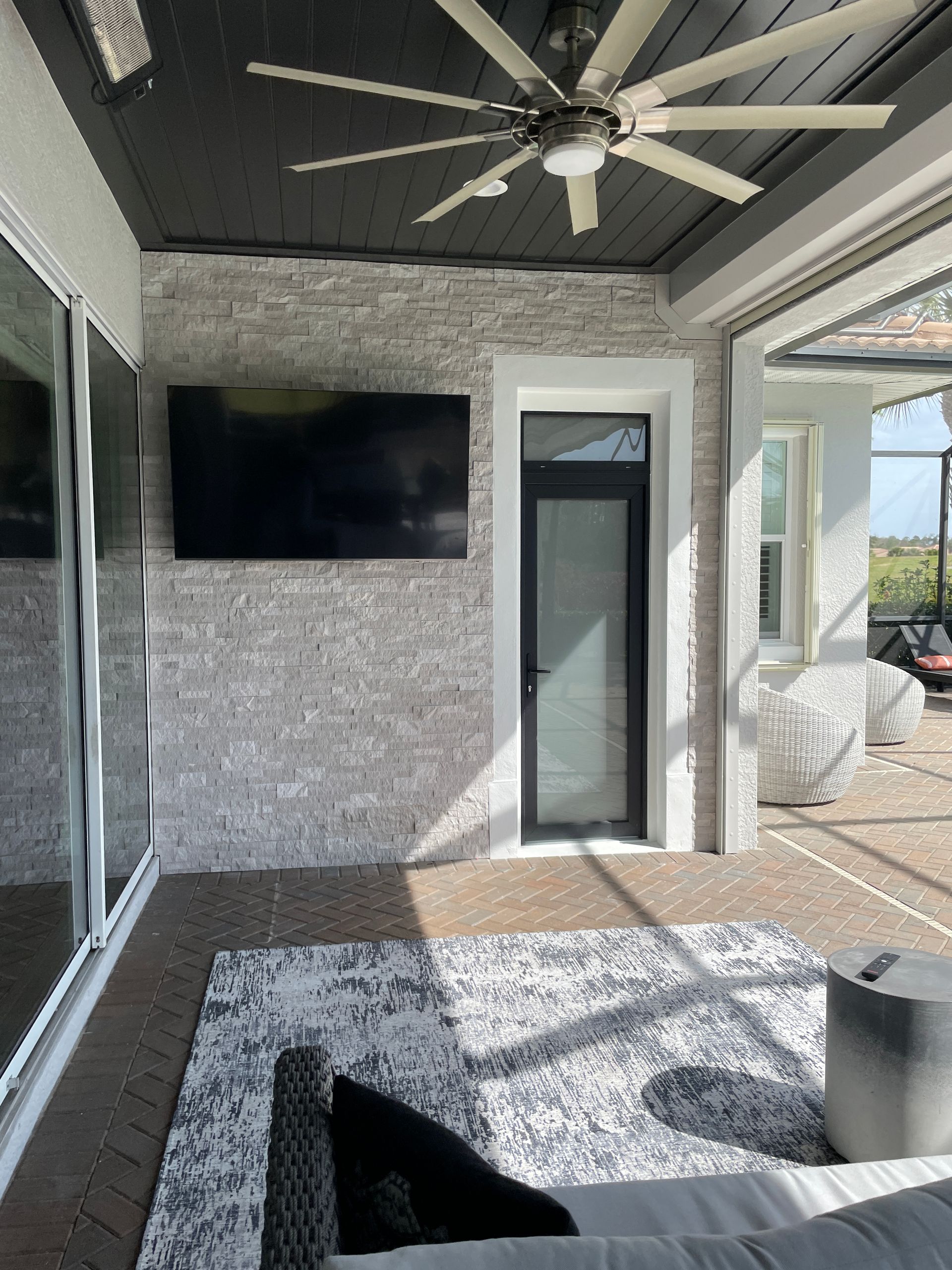 A living room with a ceiling fan and a flat screen tv on the wall.