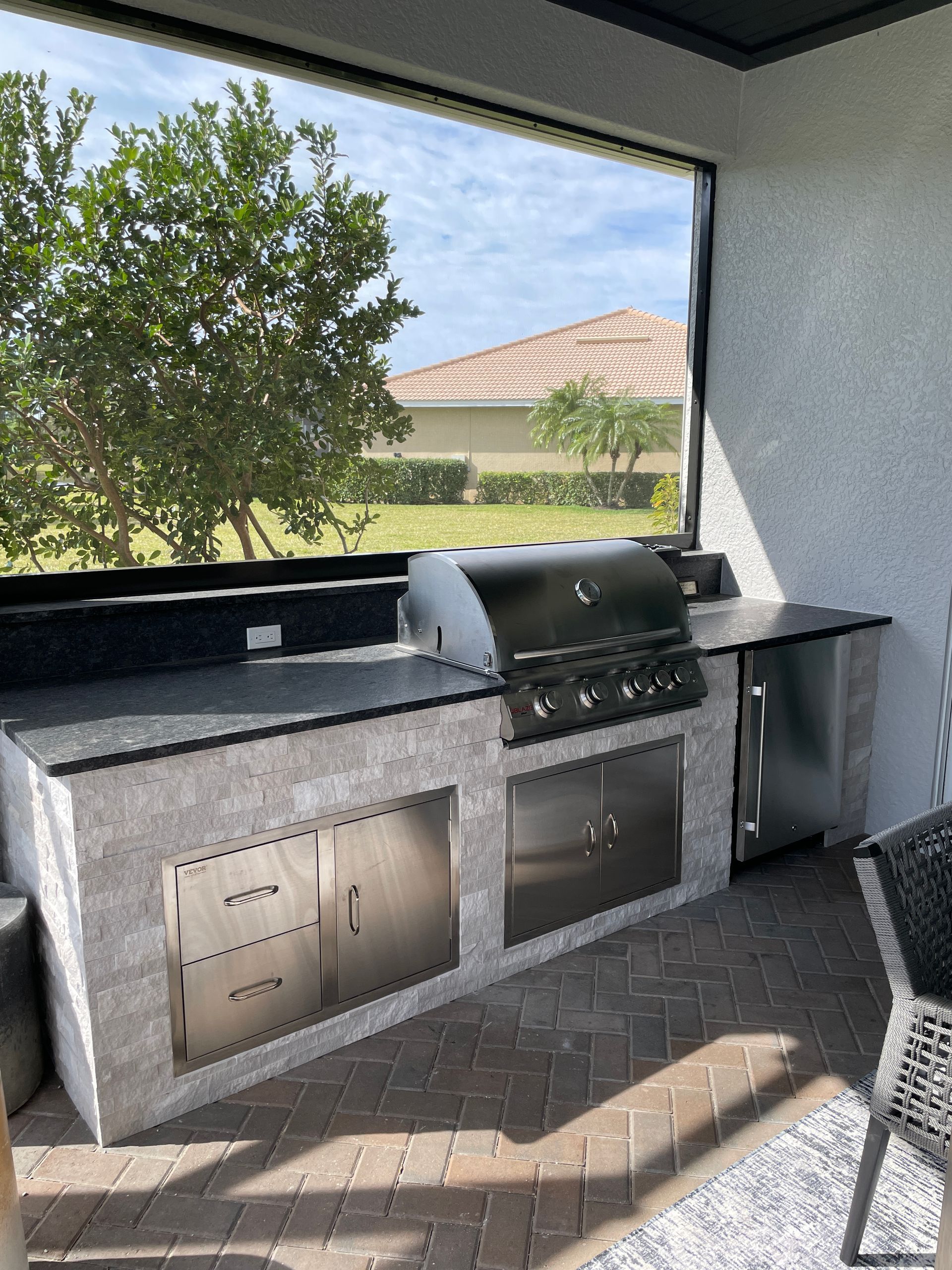 A large outdoor kitchen with a grill and a large window.