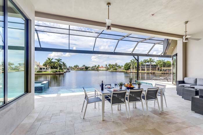 A patio with a table and chairs overlooking a lake.
