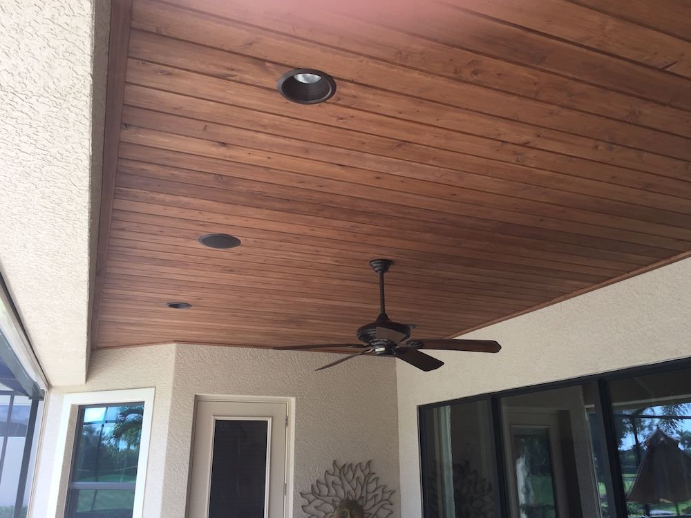 A wooden ceiling with a ceiling fan hanging from it
