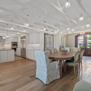 A dining room with a table and chairs and a kitchen in the background.