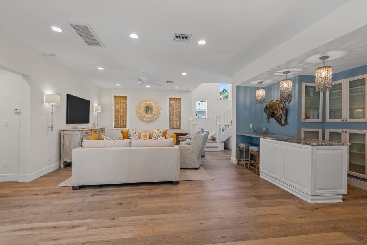 A living room with hardwood floors , a couch , a television and a bar.