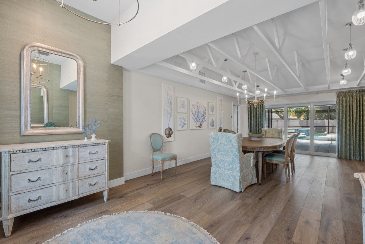 A dining room with a table and chairs and a mirror.