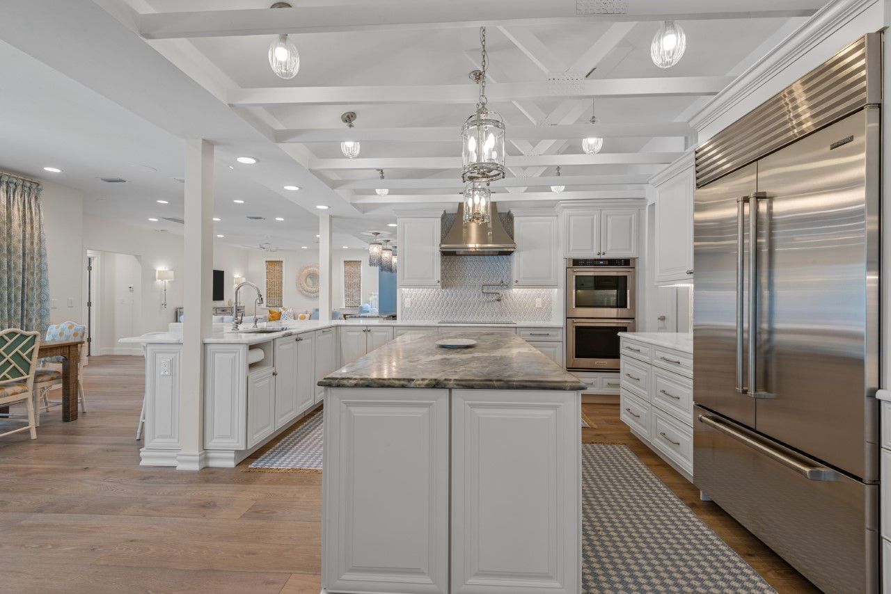 A kitchen with white cabinets , stainless steel appliances and a large island.
