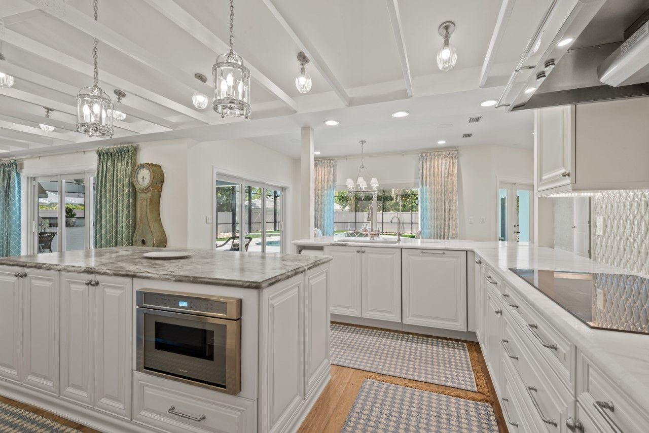 A kitchen with white cabinets , granite counter tops , stainless steel appliances and a large island.