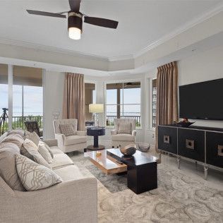 A living room with a couch , chairs , coffee table , television and ceiling fan.
