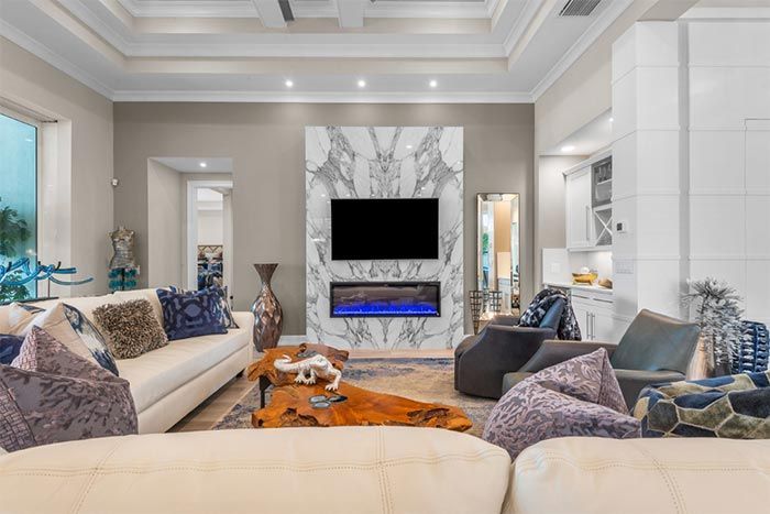 A living room with a couch , chairs , a fireplace and a flat screen tv.