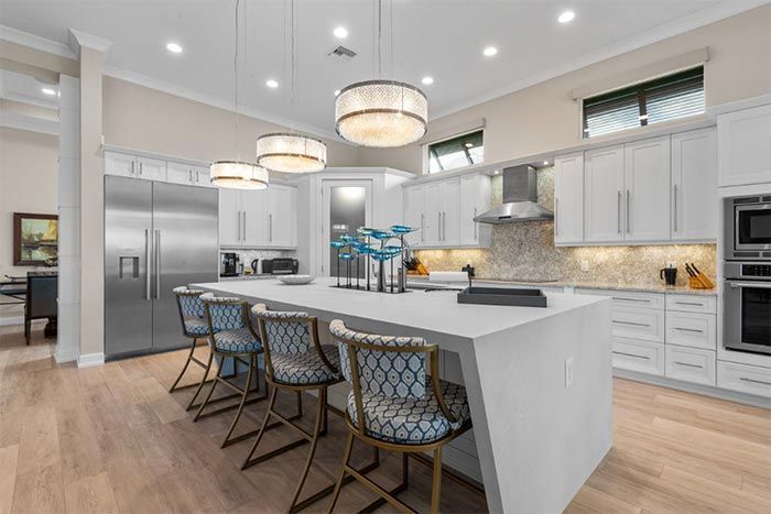 A kitchen with white cabinets and stainless steel appliances and a large island.
