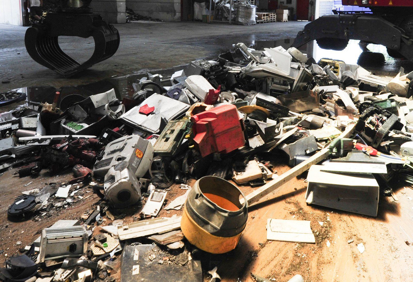 A pile of trash on the ground with a bucket of liquid in the middle