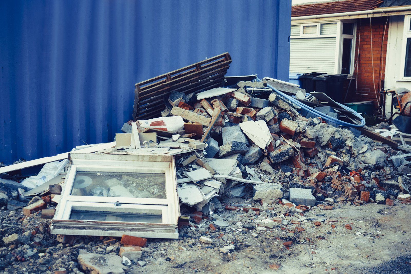 A pile of rubble is sitting in front of a blue container.