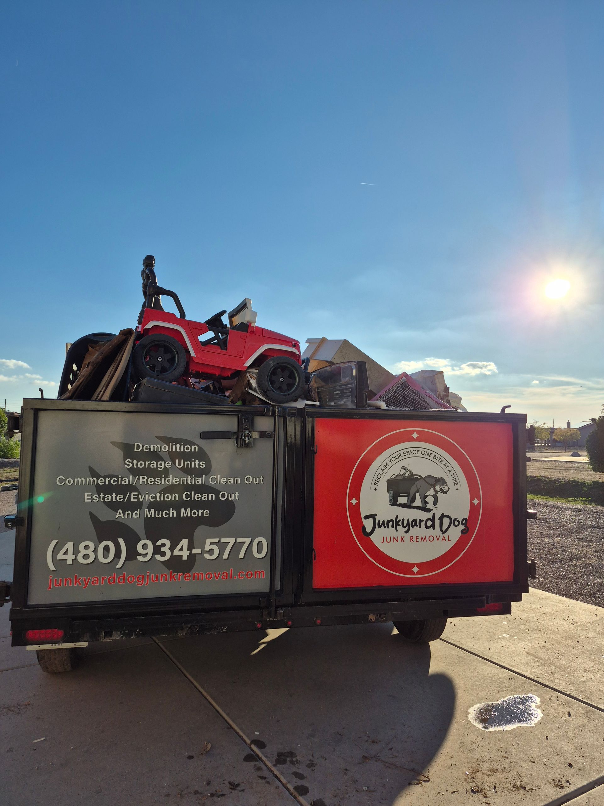 A man is holding a yellow sign in front of a pile of trash.