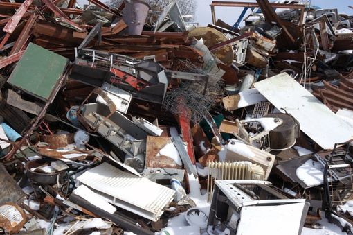 A pile of scrap metal is sitting in the snow.