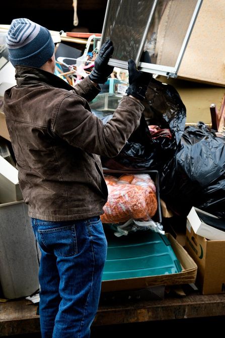A man is standing in front of a pile of garbage.