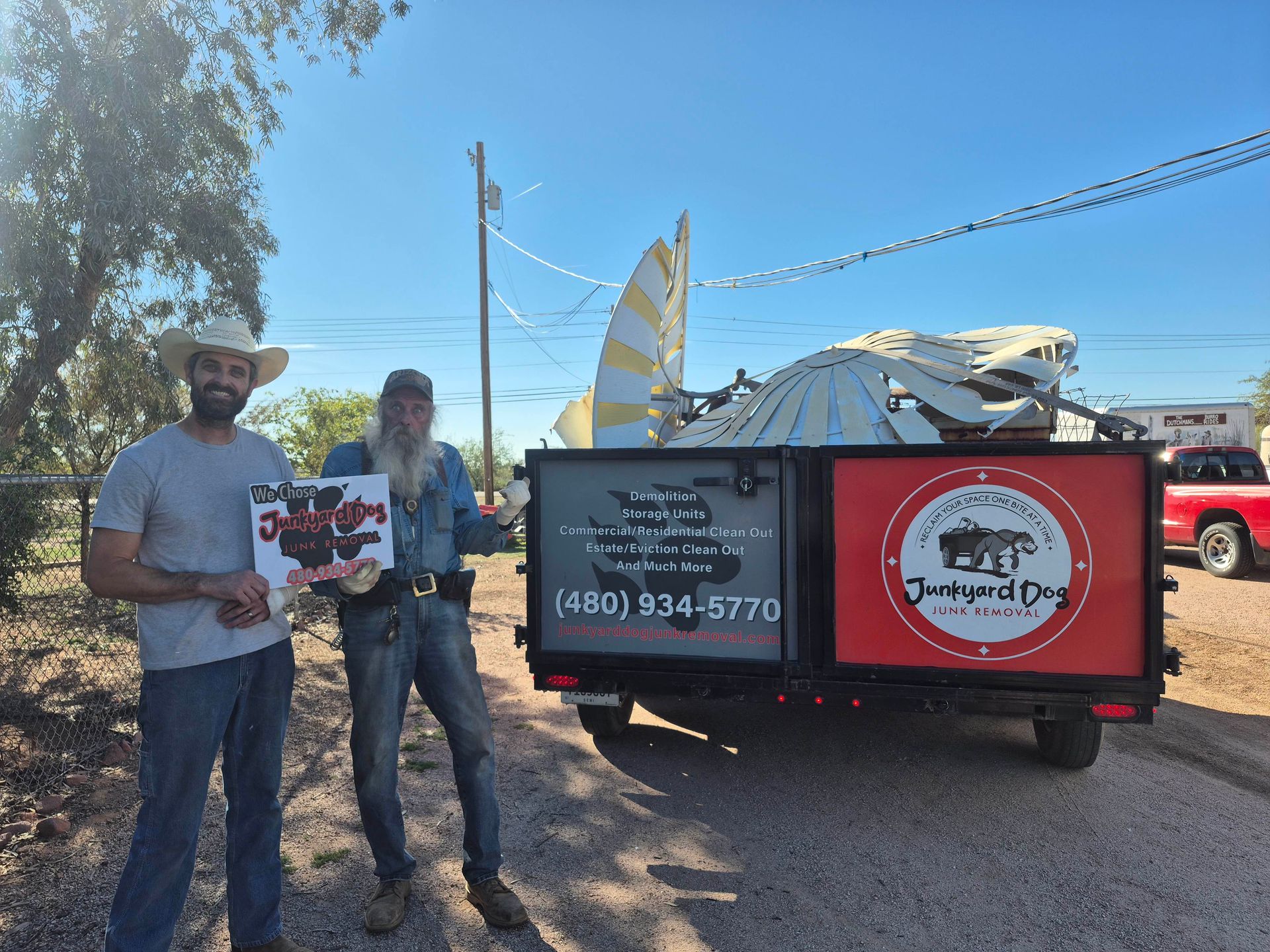 A pile of wooden pallets is sitting on the ground in front of a wooden fence.