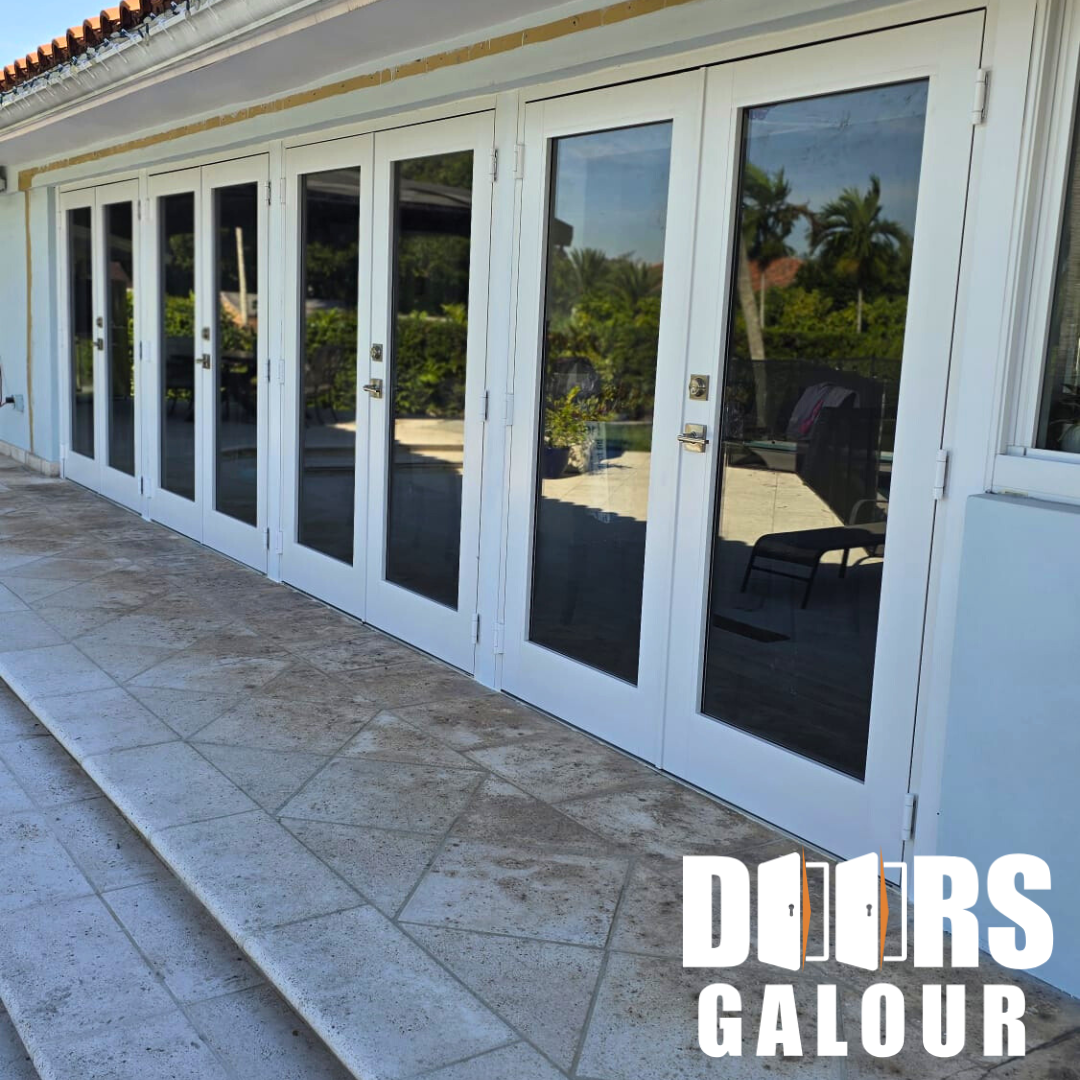 White French doors with large glass panes on a patio. Reflective glass shows outdoor setting.