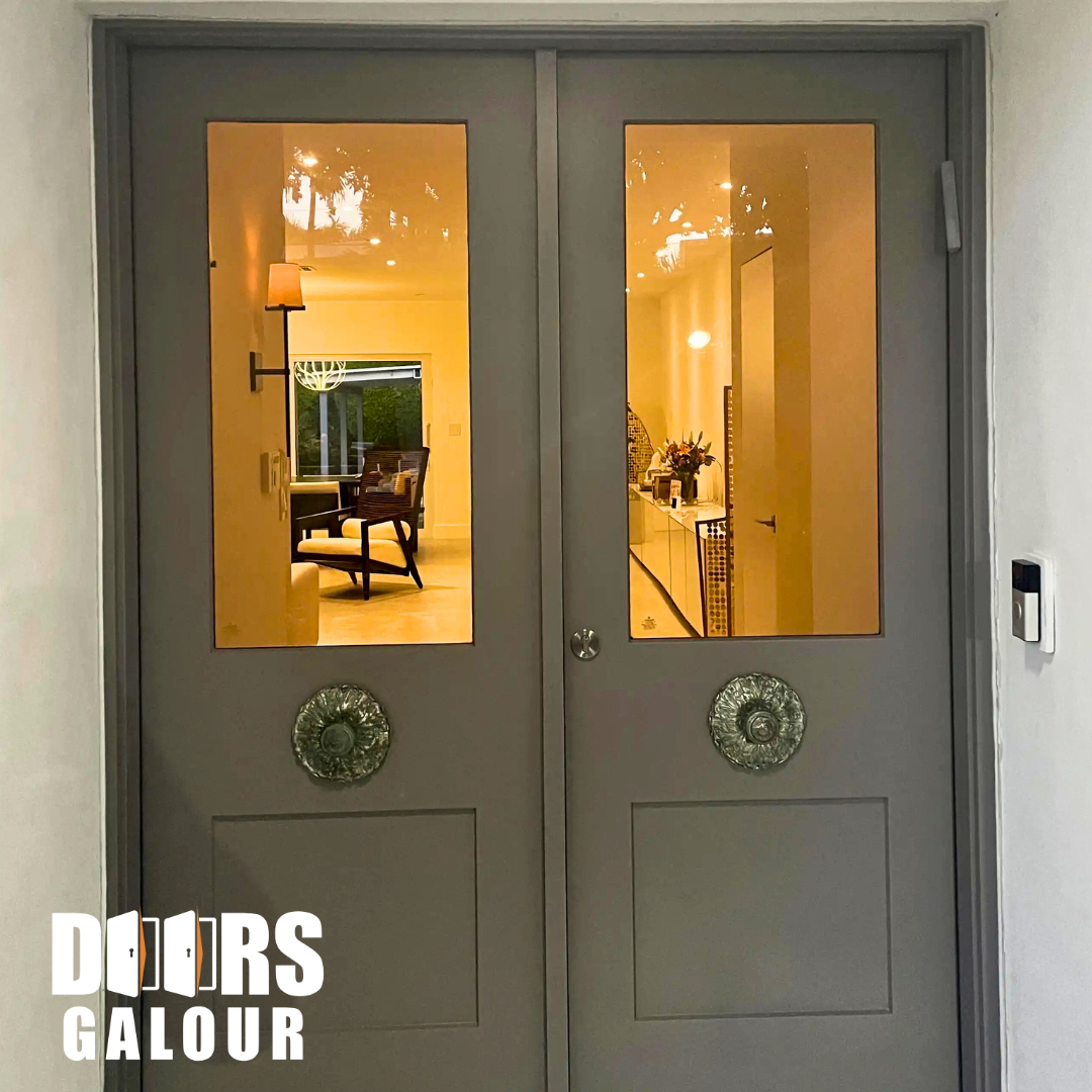 Gray double doors with glass panels and decorative hardware, reflecting a room with furniture and soft lighting.